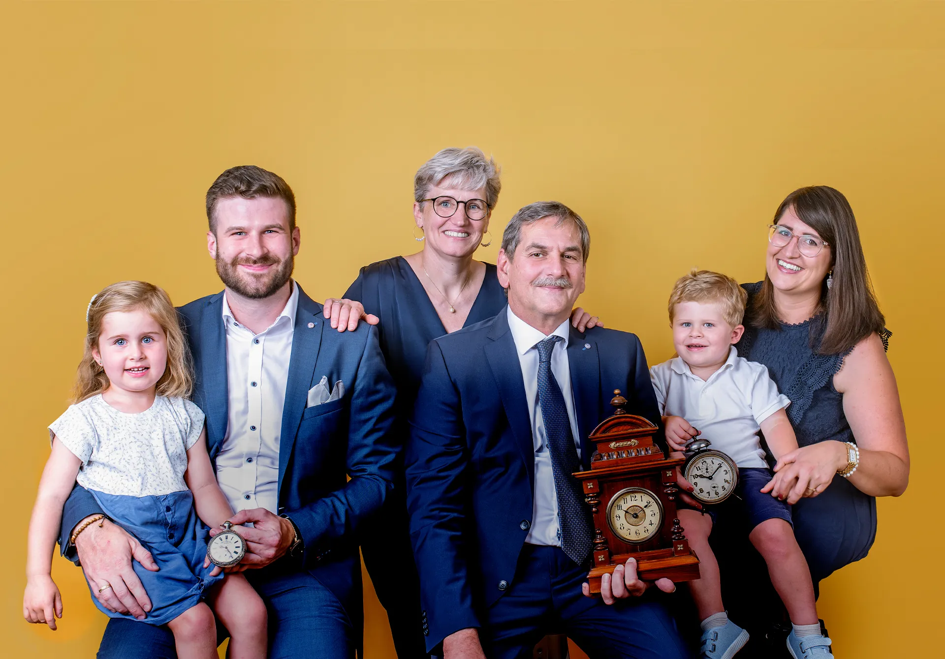 Das Team von Zeit·Punkt – drei Generationen der familiengeführten Juweliermeisterwerkstatt in Wiener Neustadt, gemeinsam vor goldenem Hintergrund lächelnd porträtiert.