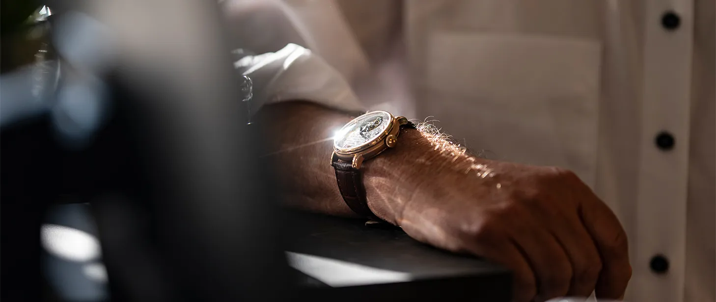 Männerarm mit elegantem Armbanduhrenmodell am Handgelenk, aufgenommen bei Tageslicht